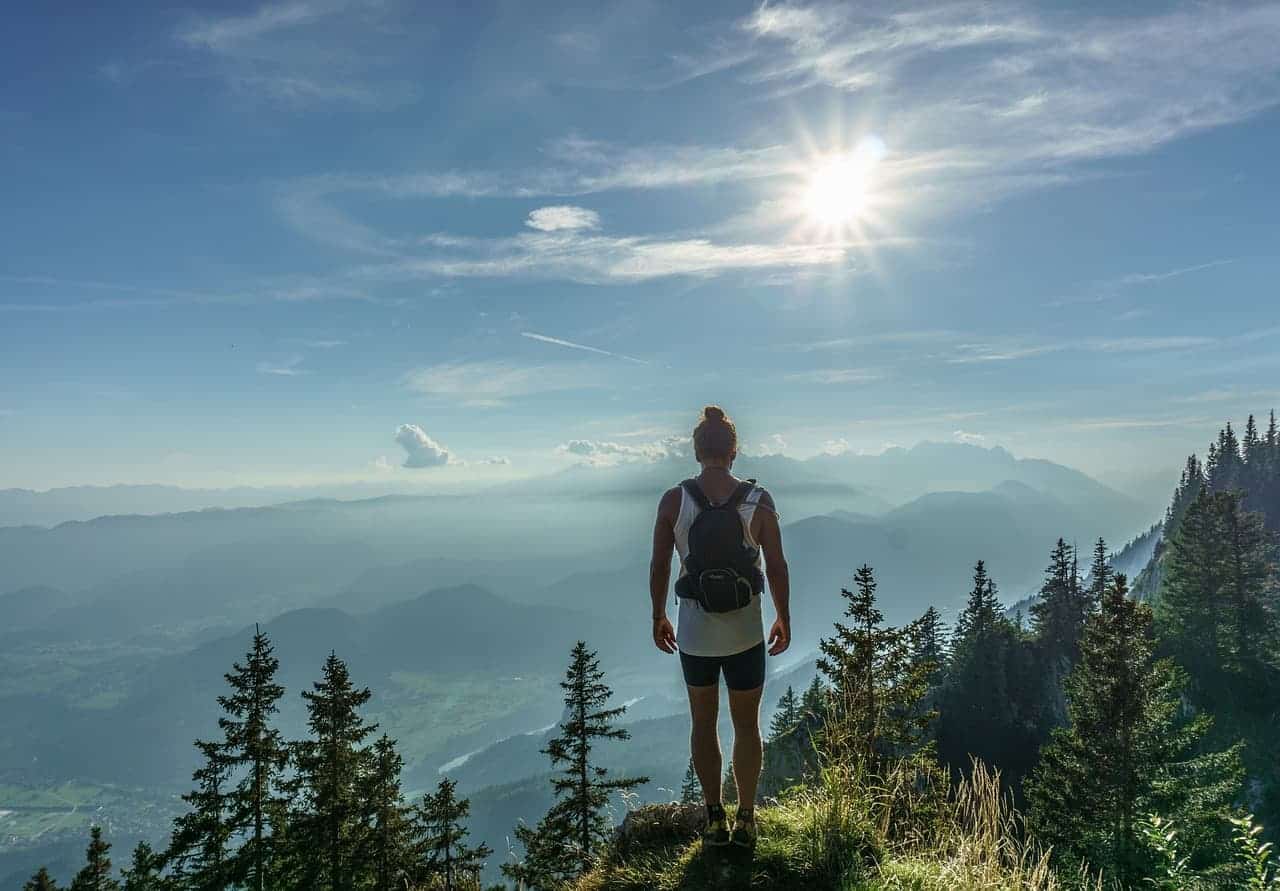 photo d'une randonneuse de dos en haut du montagne au lever du soleil